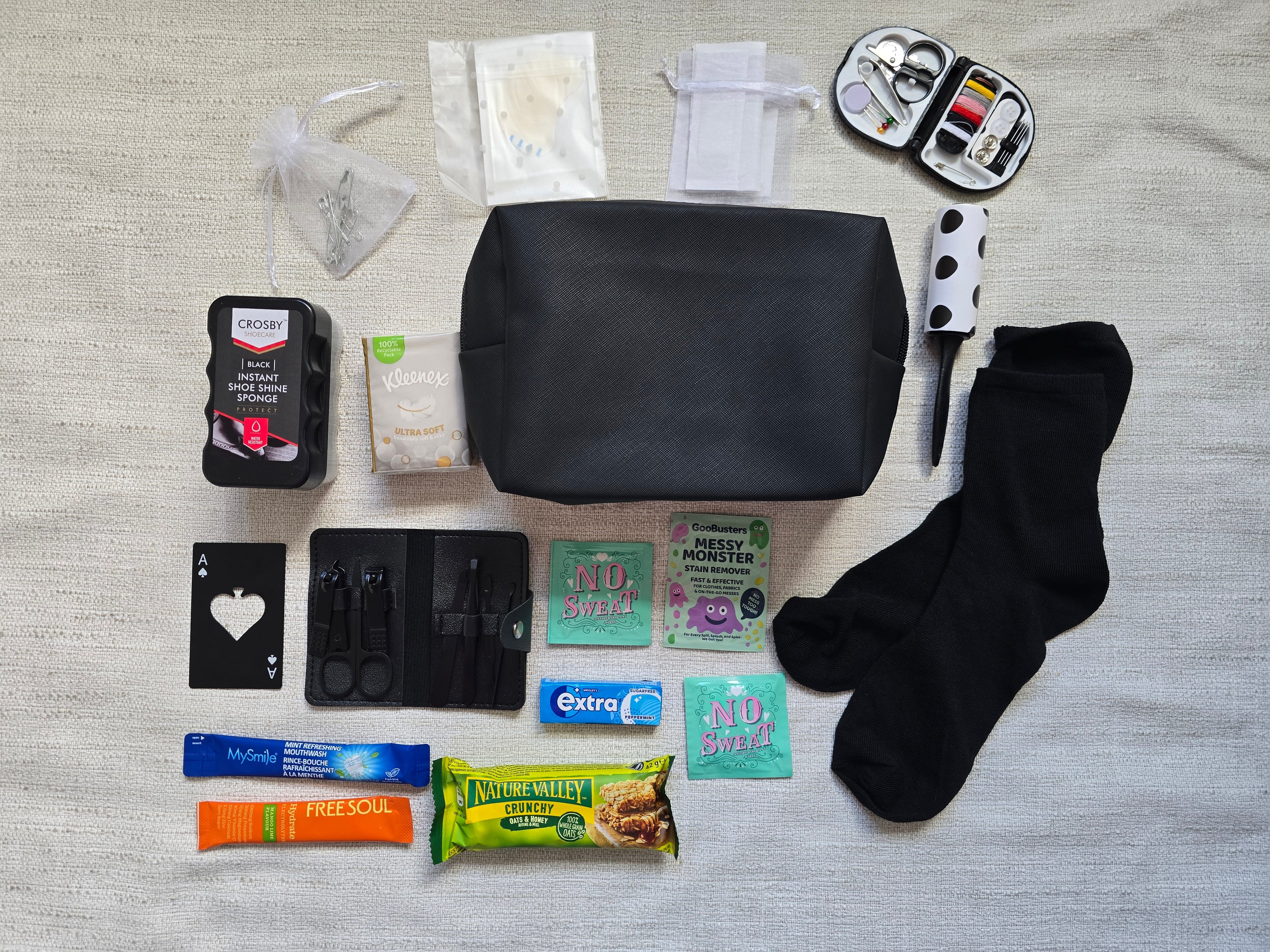Groom emergency kit contents laid out including manicure kit, sewing kit, black socks, lint roller, shoe shine sponge and grooming essentials for wedding day