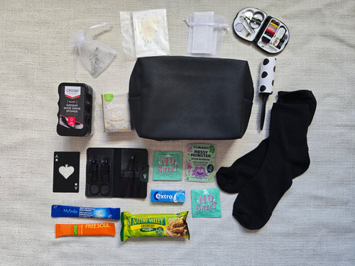 Groom emergency kit contents laid out including manicure kit, sewing kit, black socks, lint roller, shoe shine sponge and grooming essentials for wedding day